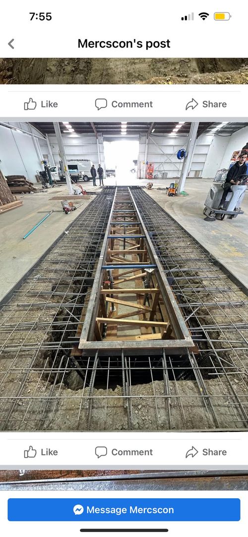 Steel framework being constructed in a large industrial warehouse with workers in the background.